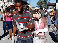 Casal ferido caminha nas ruas de Porto Príncipe em busca de ajuda.AFP/Thony Belizaire