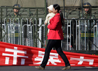 2009年9月6日在乌鲁木齐市一名妇女从军人的防线前经过。(Photo : Reuters)