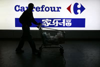 A customer in front of a Carrefour sign in Shanghai(Photo: Reuters)