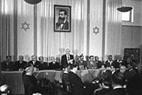 David Ben-Gurion declares the foundation of Israel, under a picture of Theodor Herzl(Photo: Wikimedia)