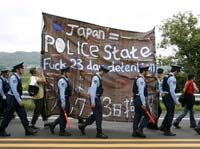 Police walk next to demonstrating anti-G8 summit protesters(Credit: Reuters)