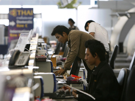 Airport workers start up computers at the check-in counter at Bangkok's International Airport.(Credit: Reuters)