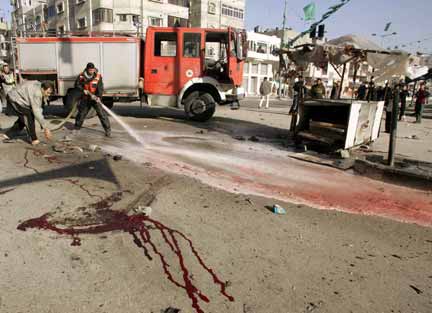 A Palestinian firefighter uses a hose to clean blood on a street in Gaza (Photo: Reuters)
