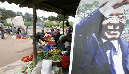 Traders by a Mugabe poster in Harare(Photo: Reuters)