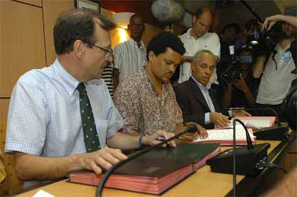 Guadeloupe prefect Nicolas Desforges (l) and strike leader Elie Domota (c) sign a deal ending the strike, Pointe-a-Pitre, 4 March 2009(Photo: Reuters)