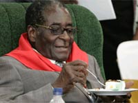 Mugabe eats cake, but wipes his hands first to prevent contracting cholera like 83,000 others in Zimbabwe(Credit: Reuters)
