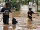A local resident trying to walk his dog through a flooded street on the outskirts of Jakarta on 27 March.(Photo: Reuters)