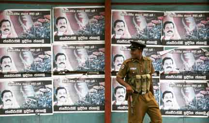 A Sri Lankan security officer walks past posters depicting President Mahinda Rajapaksa near the Presidential residence in central Colombo(Photo: Reuters)