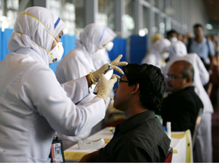 Malaysia's health officials check temperature on passengers arriving from Los Angeles for swine flu at Kuala Lumpur.(Photo: Reuters)