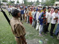 A policeman watching a queue of voters in Champashari village on the outskirts of Siliguri city on 30 April 2009(Photo: Reuters)