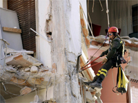 A firefighter working on a destoyed building in L'Aquila on 7 April(Photo: Reuters)