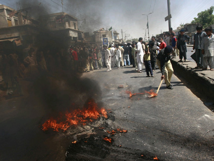 A Pakistani policeman removes burning tyres set alight by protesters in Karachi on Thursday.
(Photo: Reuters)