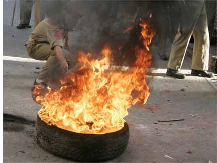 An Indian policeman tries to remove a burning tyre during a protest in Srinagar, 30 June 2009. (Photo: Reuters/Danish Ismail)