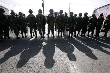 Soldiers stand guard as supporters of Honduras' ousted President Manuel Zelaya arrive after a march at Toncontin international airport Saturday 4 July(Photo: Reuters)