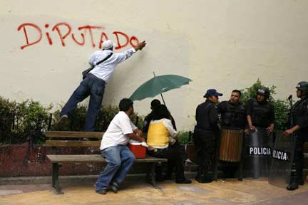 A supporter of Honduras' ousted president Manuel Zelaya spray-paints graffiti during a protest outside the National Congress building (Photo: Reuters)