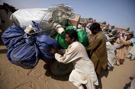 Internally displaced men in Swabi district push a cart with their belongings towards a bus due to take them back to the Swat valley on 14 July, 2009(Photos: Reuters/Adrees Latif)