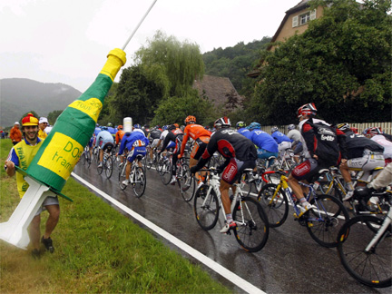 The pack of riders cycles past a spectator with a giant syringe during the 13th stage of the Tour de France Friday.(Photo: Reuters)