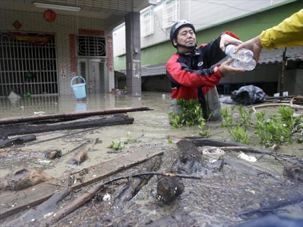 A man receives bottled water from rescue personnel in his flooded yard after Typhoon Morakot hit Pingtung county, southern Taiwan, 9 August 2009. (Photo: Reuters)