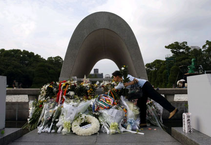 A woman places a flower for atomic bomb victims in front of a cenotaph at the Peace Memorial Park in Hiroshima, Japan on 5 August 2009(Photo: Reuters/Issei Kato)