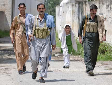 Armed men, who recently returned to their village, walk past a school girl while providing security in Buner district(Photo: Reuters)