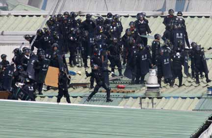 Riot policemen throw rocks toward striking workers of Ssangyong Motor running away on top of factories (Photo: Reuters)