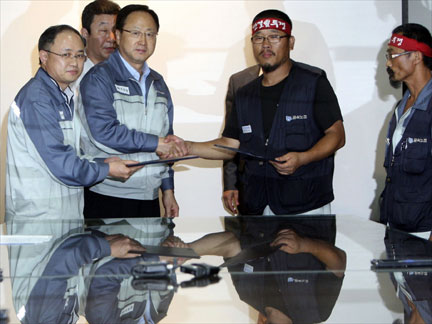 Management and workers sign agreement.Photo: Reuters