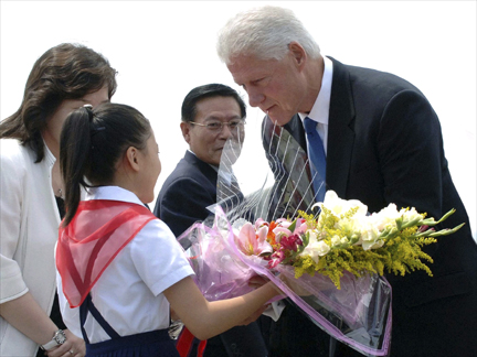 Former US President Bill Clinton receives flowers after arriving at Sunan airport in Pyongyang on 4 August(Photo: Reuters)