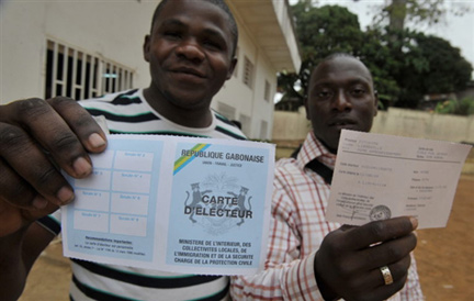 Two men hold up their electoral cards outside a registration centre in Liberville, 25 August 2009.(Photo: AFP)