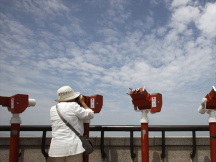 A visitor looks at a village in North Korea's Kaepoong county on Monday through binoculars from a South Korean observation post near the demilitarized zone separating the two Koreas(Photo: Reuters)