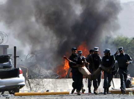 Police carry a casualty of Tuesday's suicide bomb outside the military air base in Kabul (Photo: Reuters)