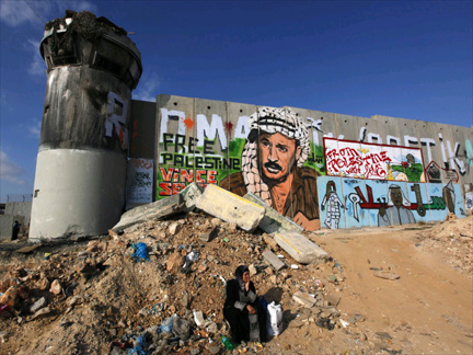 A Palestinian woman sits by the controversial Israeli barrier outside the West Bank city of Ramallah.(Photo: Reuters)