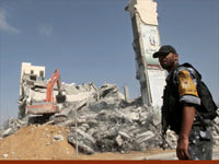 Hamas security force member stands guard as workers clear the rubble of the Palestinian parliament building in Gaza City(Credit: Reuters)