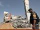 Hamas security force member stands guard as workers clear the rubble of the Palestinian parliament building in Gaza City(Credit: Reuters)