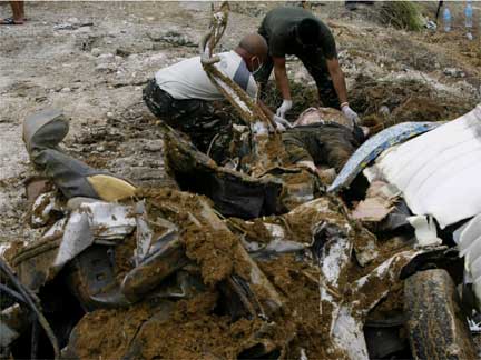 Soldiers retrieve more bodies from a shallow grave at the massacre site(Photo: Reuters)