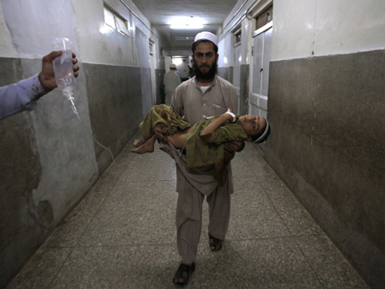A father carries his son, who was injured in the suicide bomb attack, through the halls of a hospital in Peshawar after he was treated.(Photo: Reuters)