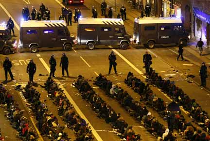 Arrested demonstrators sit on the ground, surrounded by police (Photo: Reuters)