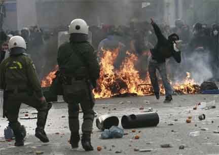A protester throws a stone at riot police in central Athens, 6 December 2009(Photo: John Kolesidis/Reuters)