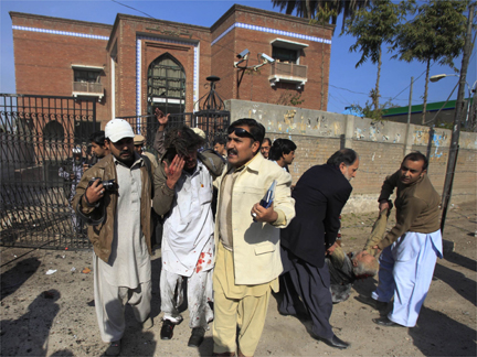 Journalists assist an injured man at the gate of the press club in Peshawar on 22 December(Photo: Reuters)
