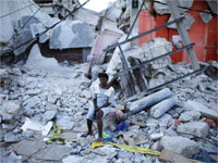 A woman sits in front of a destroyed building in Port-au-Prince(Credit: Reuters)
