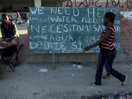 A woman walks in front of a sign in downtown Port-au-Prince(Photo: Reuters)