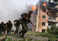 Soldados georgianos corren junto a un edificio en llamas tras un bombardeo ruso en Gori.Reuters