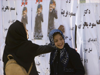 دختران دانش آموز در مقابل لیست کاندیداهی انتخابات مجلس ایران.(عکس: رویترز)