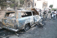 Des militaires américains devant la carcasse brûlée d'une voiture stationnée près d'une église à Mossoul. 

		(Photo : AFP)
