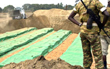 Le 17 août 2004, le personnel de l'ONU recouvre la fosse commune où sont inhumés les quelque 160 morts de Gatumba. 

		(Photo : AFP)