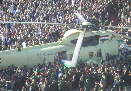 La foule déborde les services de sécurité qui tirent en l'air sans résultat pour se presser autour de l'hélicoptère d'où est extraite la dépouille de Yasser Arafat. 

		(Photo: Manu Pochez/RFI)