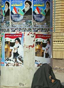 A Bagdad, une Irakienne se tient devant des affiches électorales. 

		