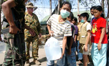 Un jeune garçon tient une poche d'eau plastifiée donnée par un soldat de l'armée australienne.(Photo : AFP)