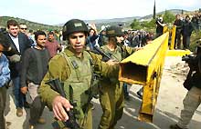 Un soldat israélien ouvre la barrière jaune du <i>check point</i> d'Anabta, près de Toulkarem, le 22 mars 2005.(Photo: AFP)