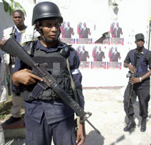 Des policiers haïtiens patrouillent devant une église recouverte de photographies du président déchu Jean-Bertrand Aristide, le 27 juin dernier. Malgré la multiplication des rondes dans les quartiers de Port-au-Price avec le soutien des troupes de l'ONU, la violence et  les kidnappings ne cessent d'augmenter.(photo : AFP)