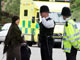 La police britannique interroge les passants dans la banlieu de Londres.Photo : AFP